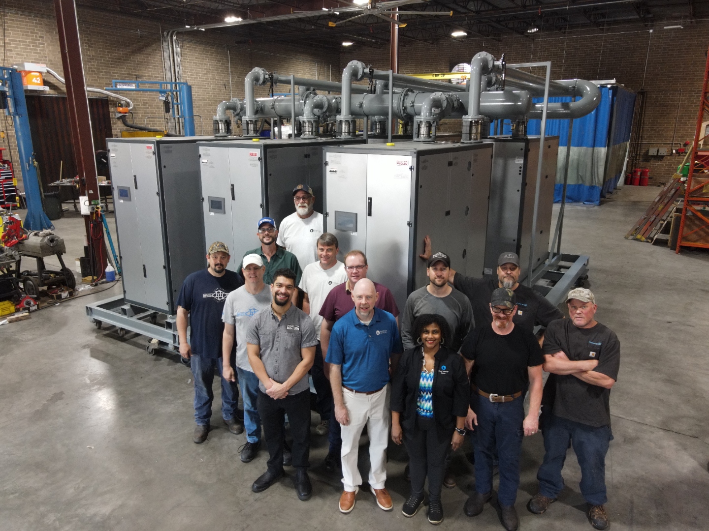 The Pump'nFlo team standing together in the shop with a completed mechanical skid